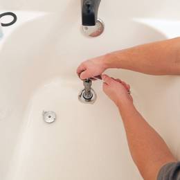 A man fixing a faucet in a bathtub.