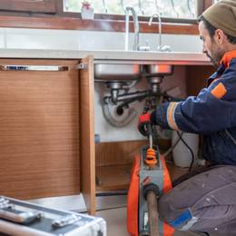 A plumber working on a kitchen sink.