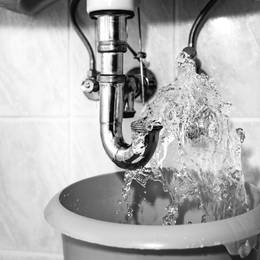 A black and white photo of a sink with water coming out of it.