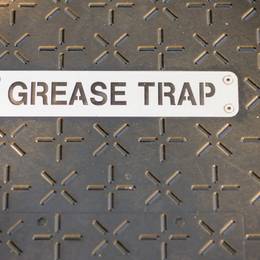 A sign that says grease trap on a metal surface.