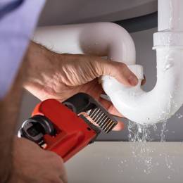 A plumber is working on a pipe in a bathroom.