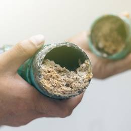 A person is holding a green pipe with dirt in it.