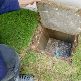 A man pouring concrete into a hole in the ground.