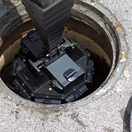 A black device is sitting in a hole in the ground.