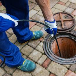 A man using a hose to clean a manhole.