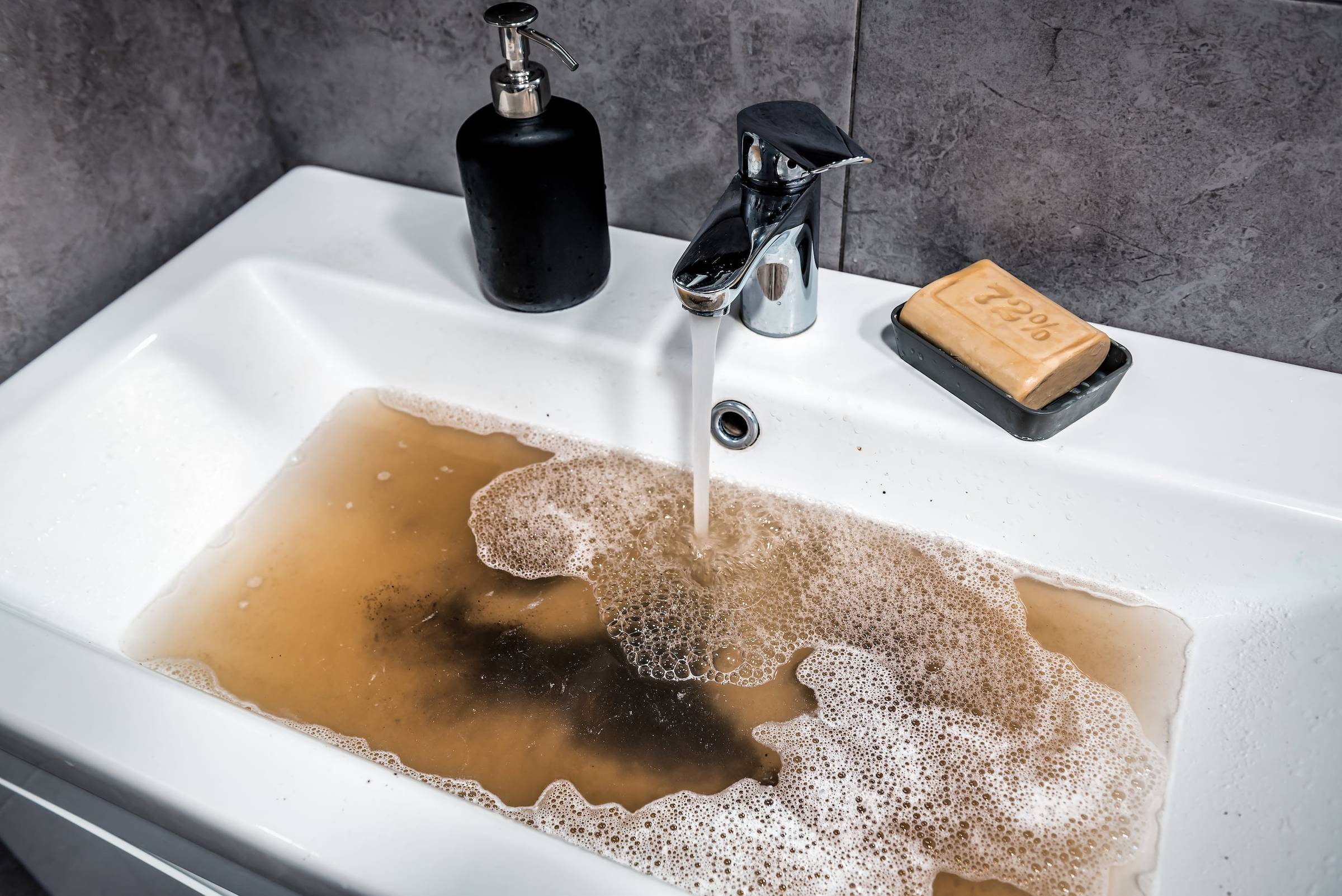 A man fixing a faucet in a bathtub.