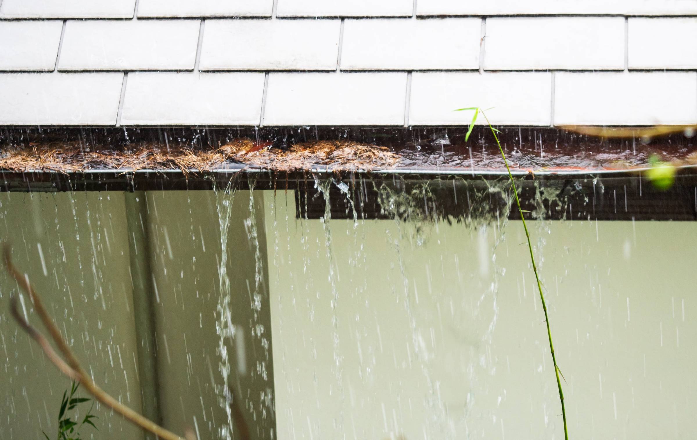 A house with a roof that is being drenched in rain.