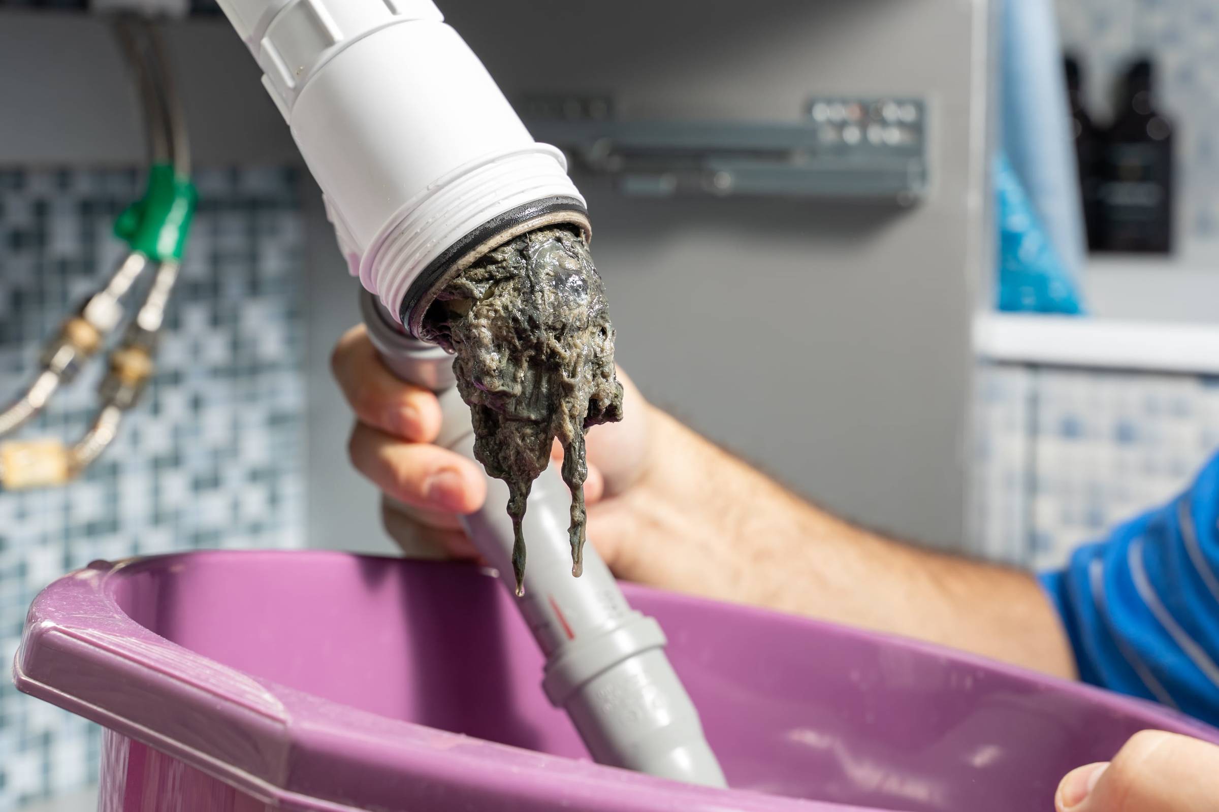 A man cleaning a sink with a hose.