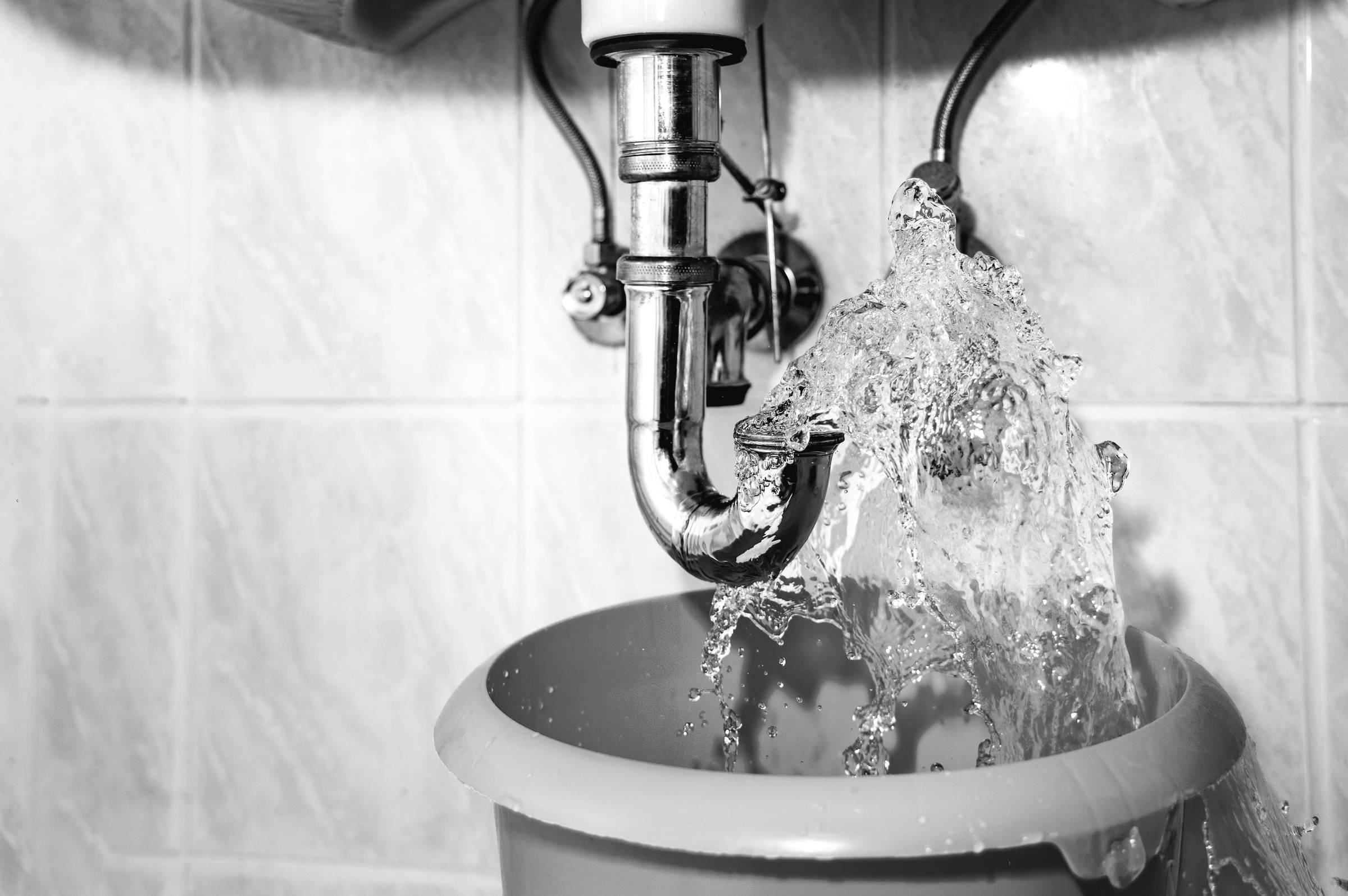 A black and white photo of a sink with water coming out of it.