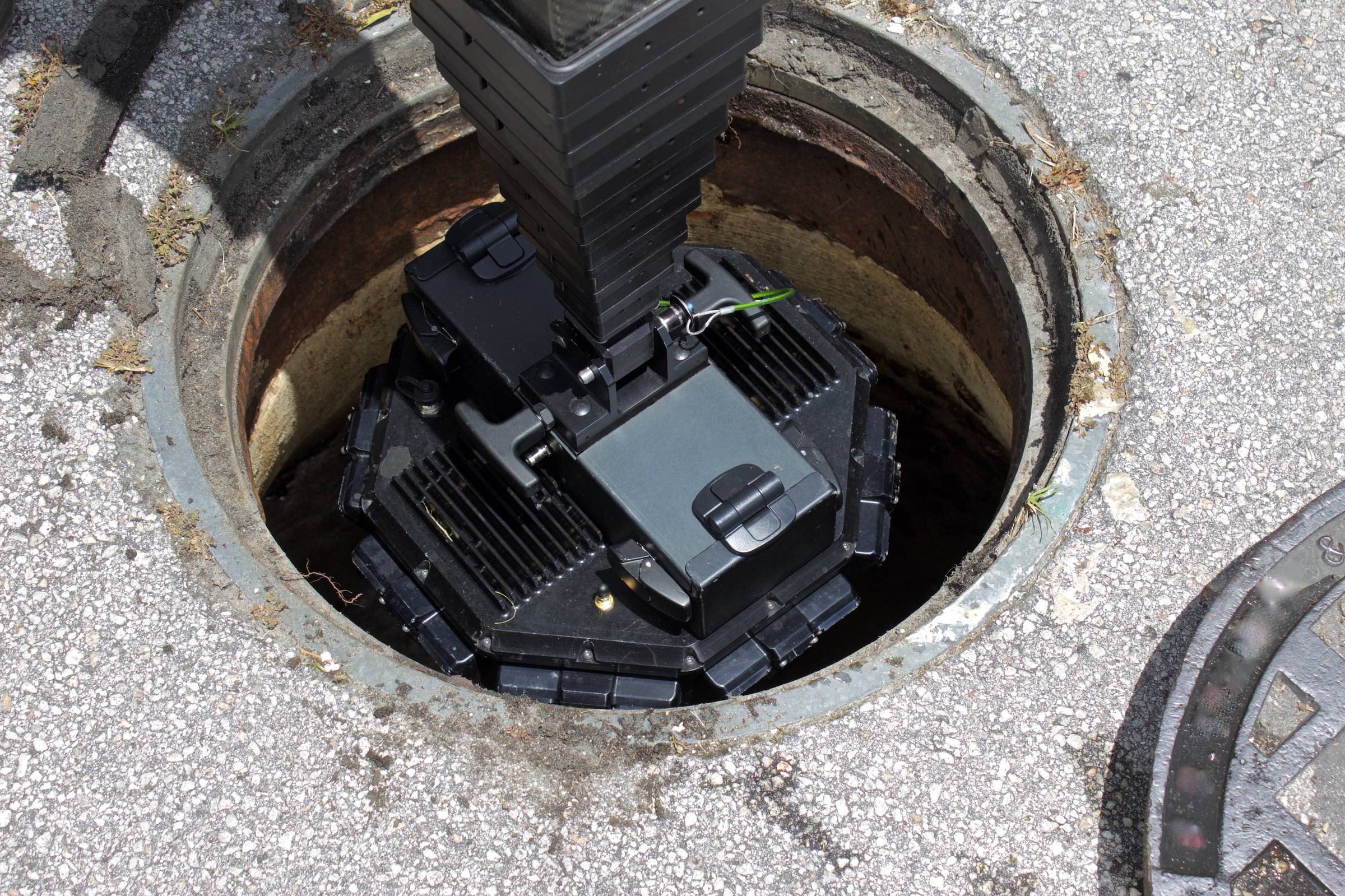 A black device is sitting in a hole in the ground.